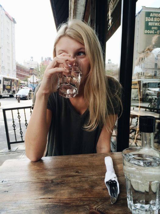 chica bebiendo un vaso de agua en un restaurante 