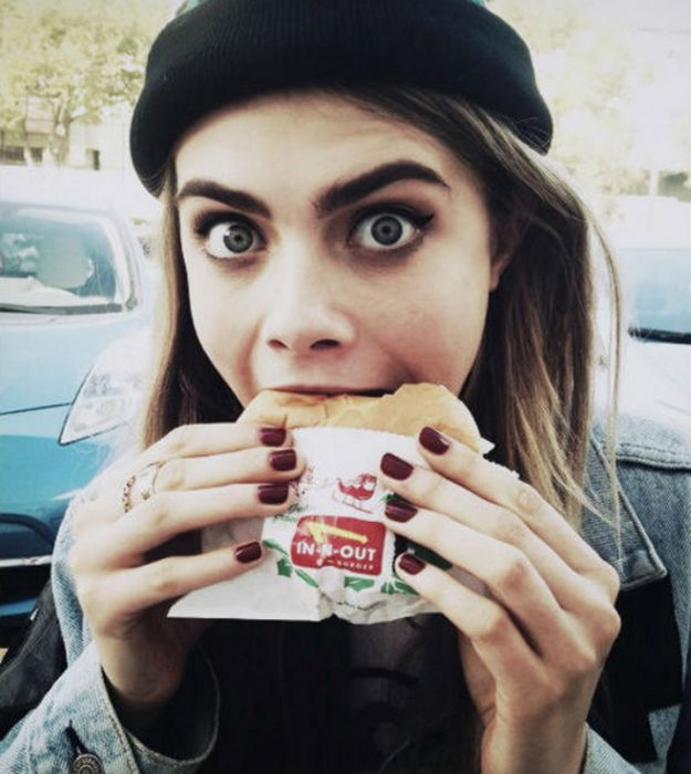 cara delavinge comiendo una hamburguesa 