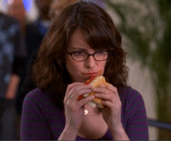 mujer de lentes comiendo una hamburguesa 