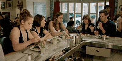 personas sentadas en la mesa de un restaurante comiendo 