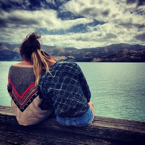 chicas sentadas abrazadas viendo el mar 