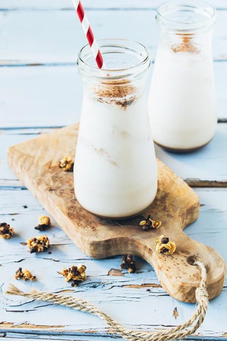 vaso con agua de horchata puesto sobre una tabla y con canela esparcida por la mesa 