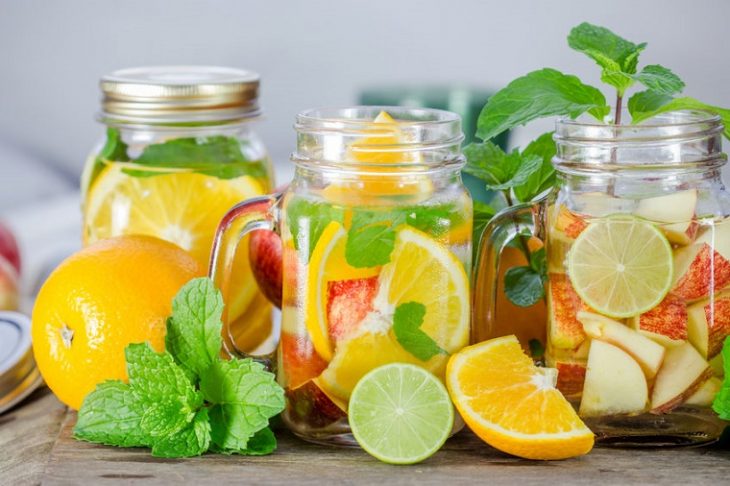 vasos con agua de cítricos como manzana, naranja y limón 