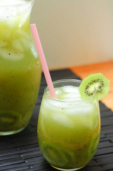 vaso y jarra con agua de kiwi puestos sobre la mesa 