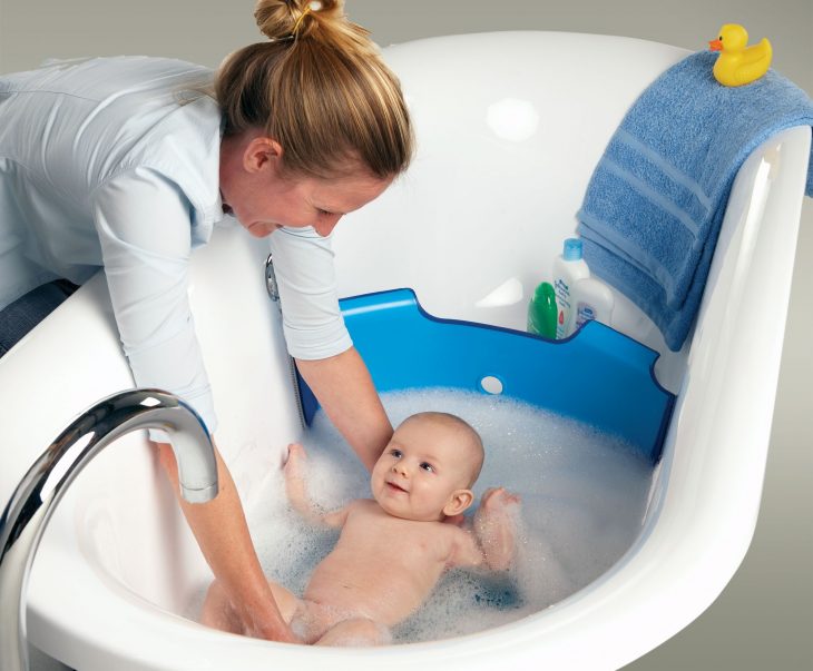 mujer bañando a su bebé en la tina del baño 