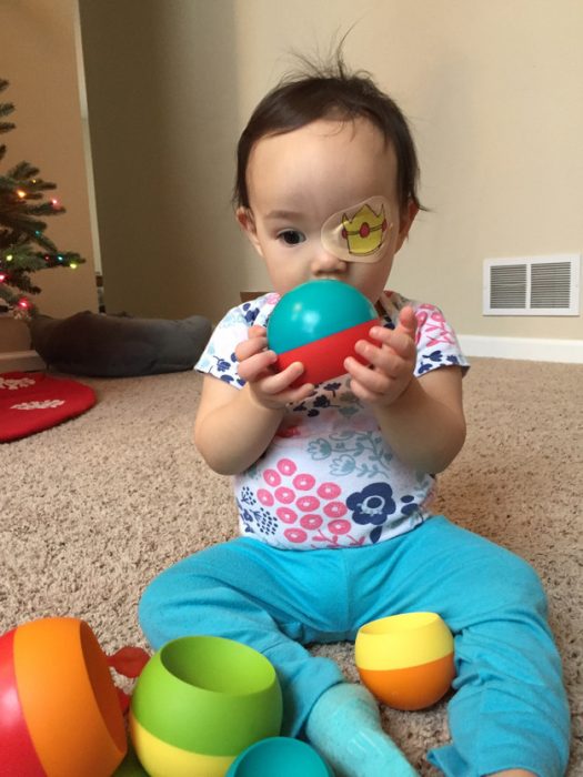 niña usando un parche en el ojo y jugando con una pelota 