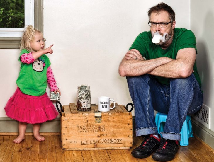 hombre sentado en un banco comiendo jabón mientras su hija lo regaña 
