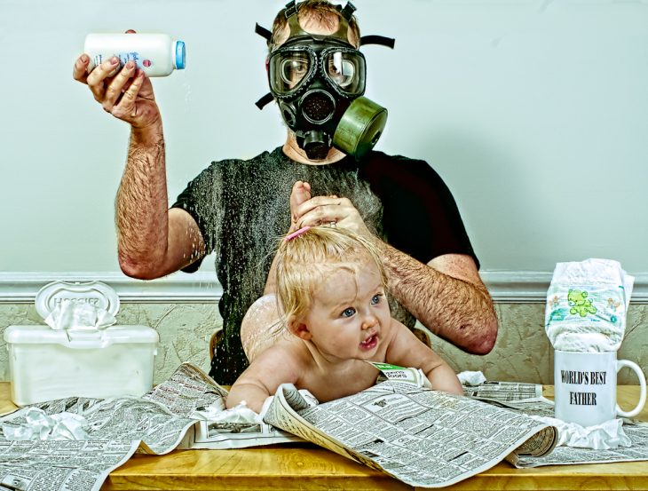hombre usando una mascara anti-gas para cambiar los pañales a su bebé 