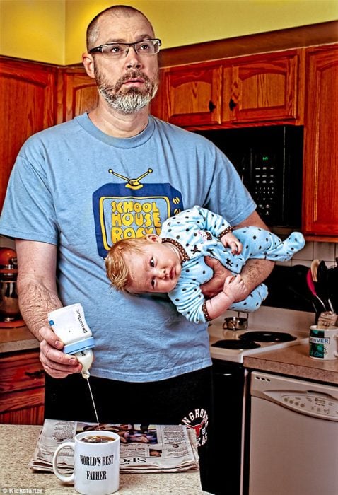 hombre preparando un café y sosteniendo un bebé en brazos 