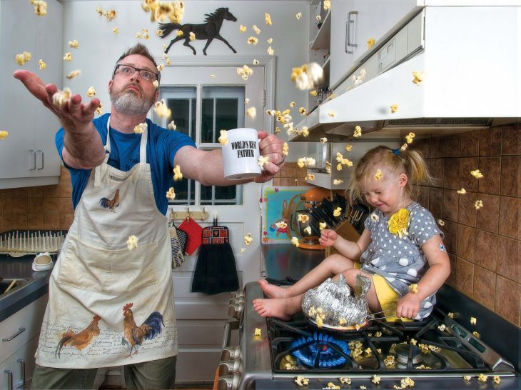 hombre cocinando palomitas con una niña en la estufa 