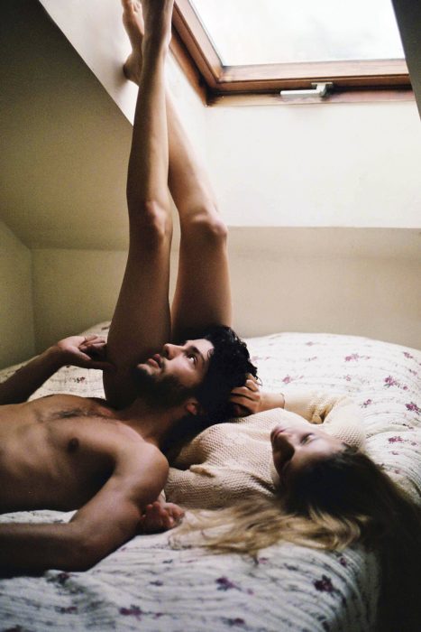 pareja de novios recostados en la cama viendo hacia la ventana 