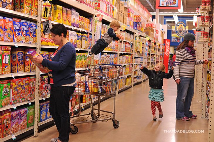 niño con síndrome de down que simula volar mientras esta con su mamá en el supermercado 
