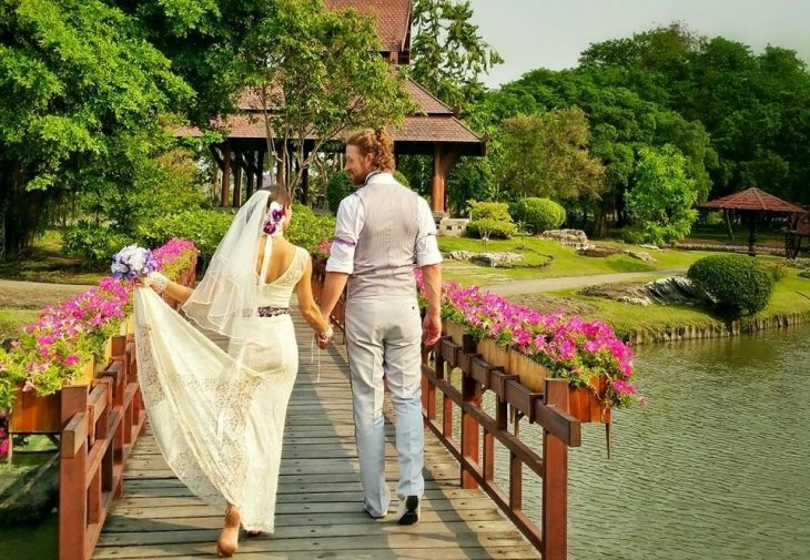 pareja de novios tomados de la mano caminando por un puente 