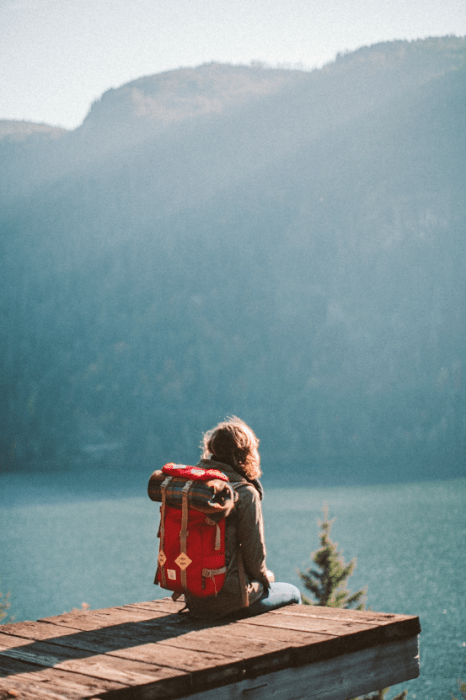 chica sentada en una montaña viendo hacia el mar 