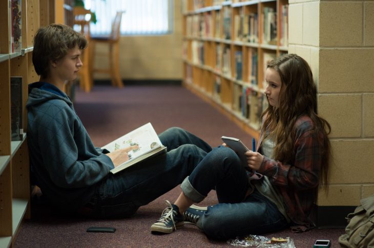 chicos en una biblioteca sentados entre los estantes de libros 