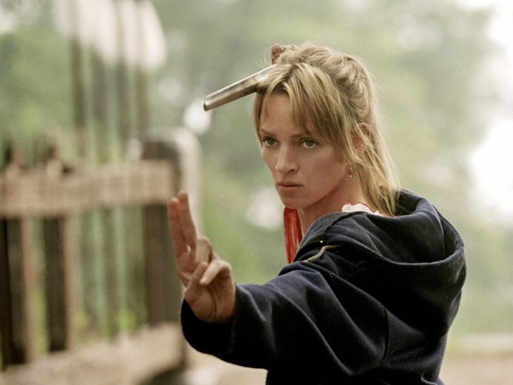 Escena de la pelícla kill bill uma turman sosteniendo una espada en su mano 