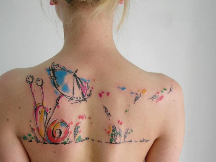 caracol tatuado en la espalda al estilo acuarela 