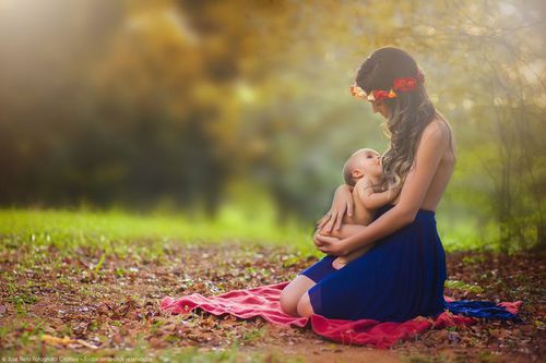 mujer sosteniendo a un bebé en brazos y dándole pecho 