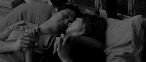 pareja de novios recostados en la cama abrazados y tocándose la cara 