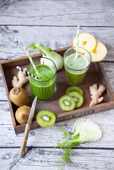 Jugo de kiwi puesto sobre una tabla con kiwis a su alrededor 