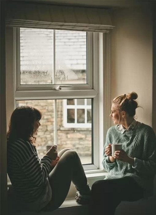 chicas platicando en una ventana tomando café 
