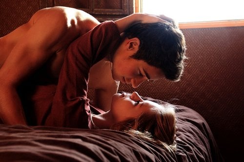pareja de novios recostados en la cama besándose 