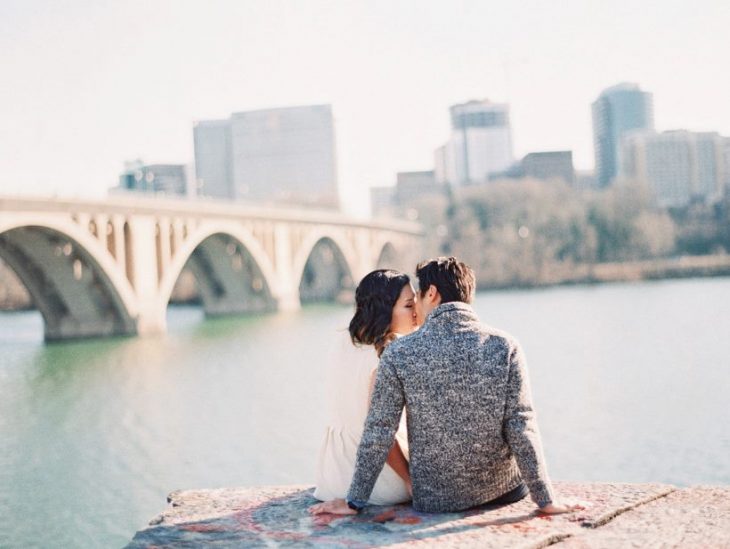 pareja de novios sentados sobre unas rocas viendo la ciudad frente a ellos 