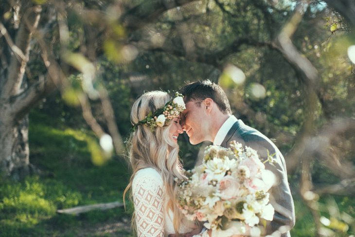 pareja de novios el día de su boda posando para una fotografía bajo un árbol 