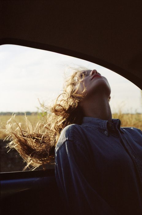 Chica con la cabeza afuera de la ventanilla de su carro 