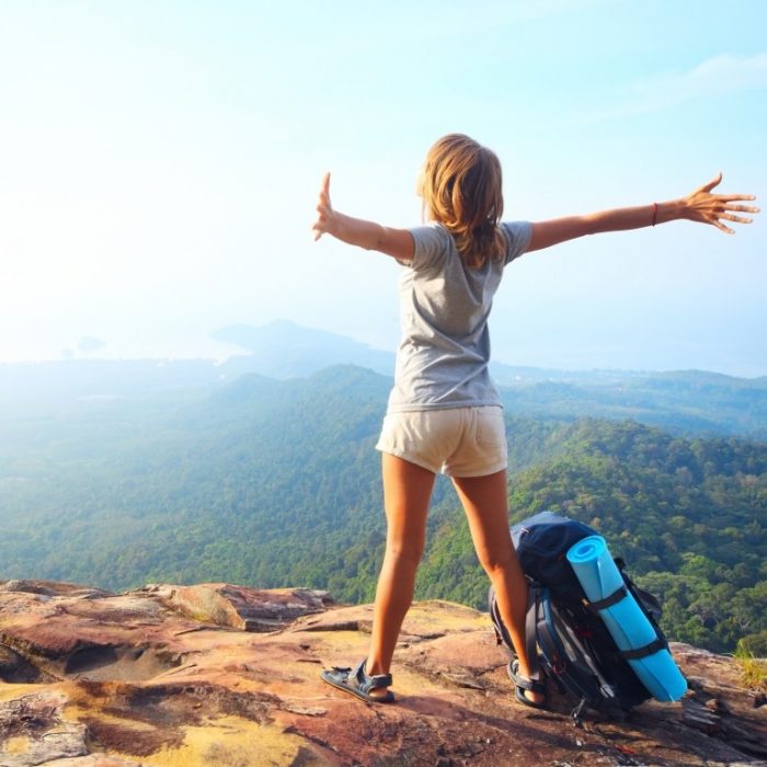 chica en una montaña con los brazos abiertos 