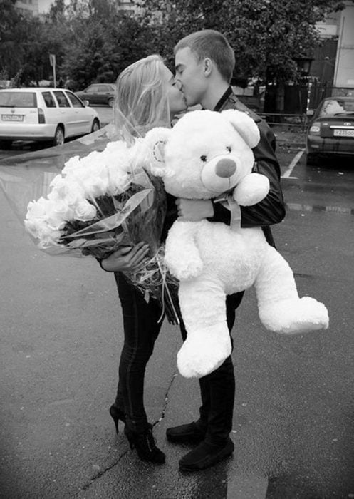 Chico regalando un oso de peluche y rosas a su novia 