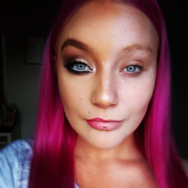 Chica de cabello rosa con la mitad del rostro maquillado para una foto de instagram 