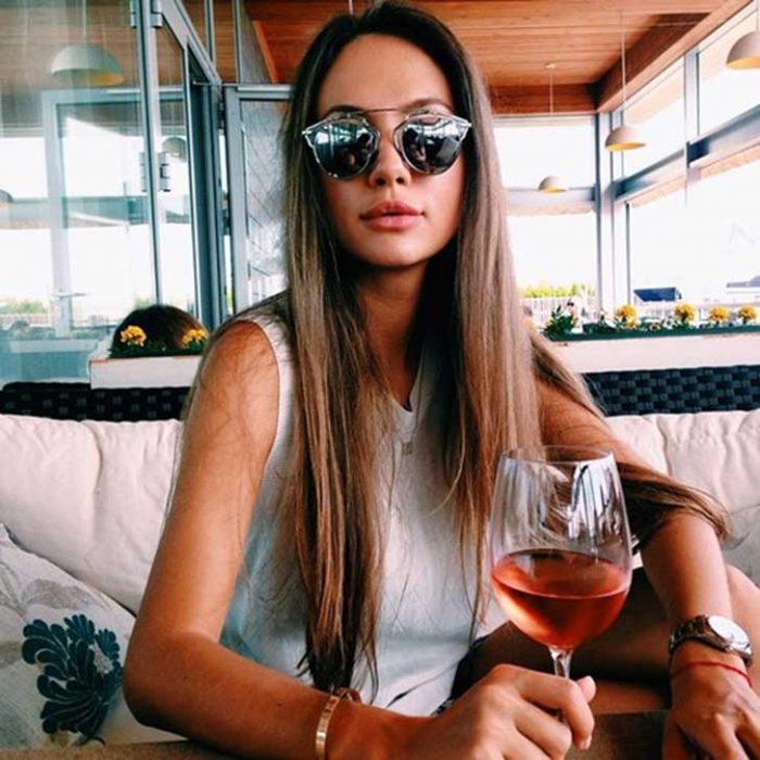 Chica tomando una copa de vino rosa 