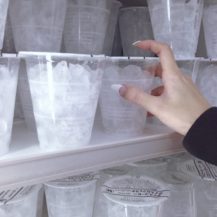 Mano dentro de un congelador tomando un vaso de hielos 