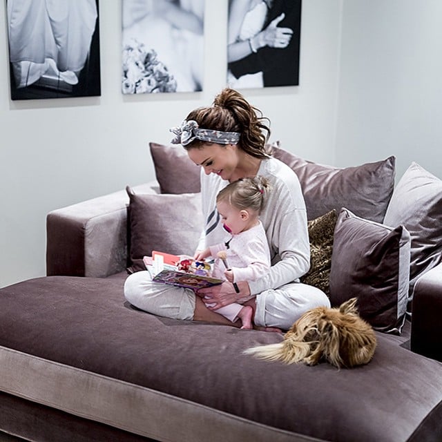 mujer sentada en un sofá con una bebé en su regazo leyendo un cuento