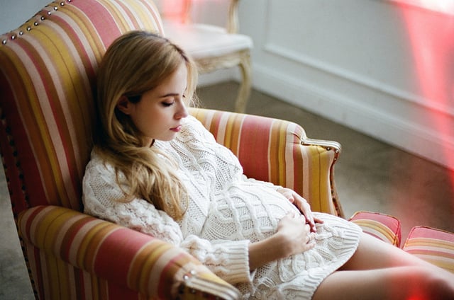 chica embarazada sentada en un sofá tocándose la pansa 