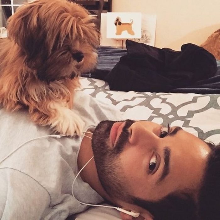 chico recostado en la cama escuchando música con su perro en el pecho 