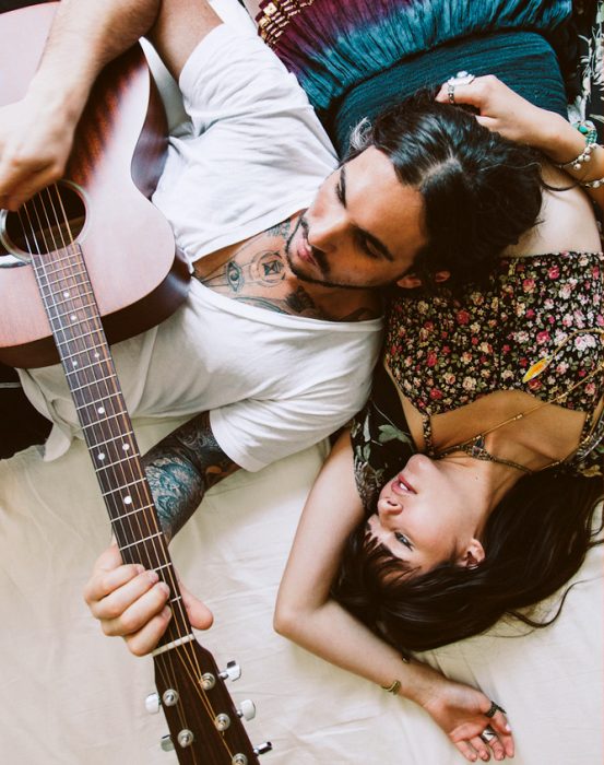 pareja acostados mientras él toca la guitarra 