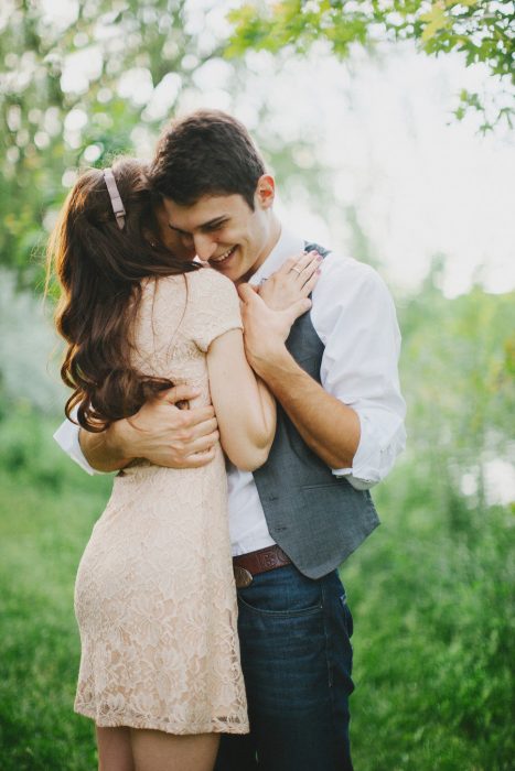 pareja de novios abrazados parados en medio de un jardín 