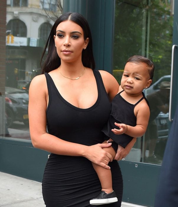 kim kardashian cargando a su hija en brazos mientras caminan por la calle 