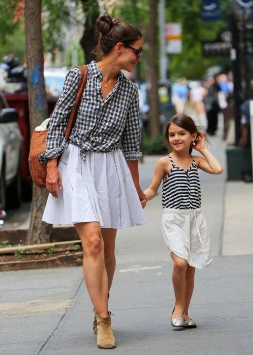 Katie Holmes y su hija suri caminando por las calles tomadas de las manos y vestidas similar con faltas y blusa negra de rayas 