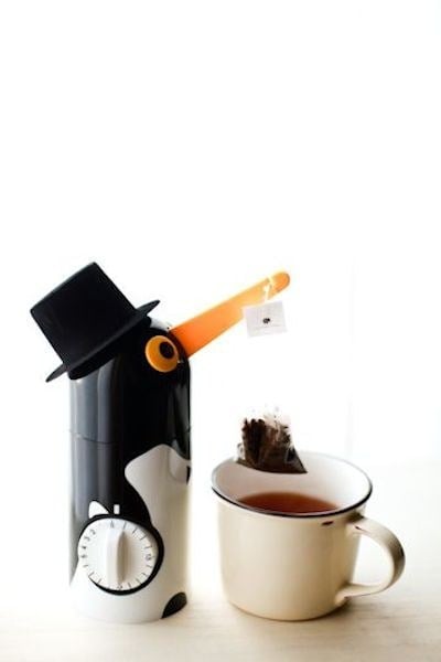 pinguino que sostiene un infusor de té 