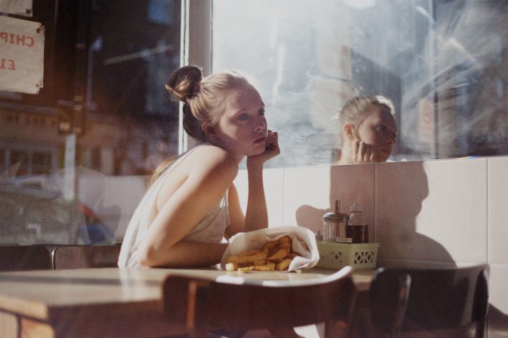 chica sentada en un restaurante comiendo y pensando 