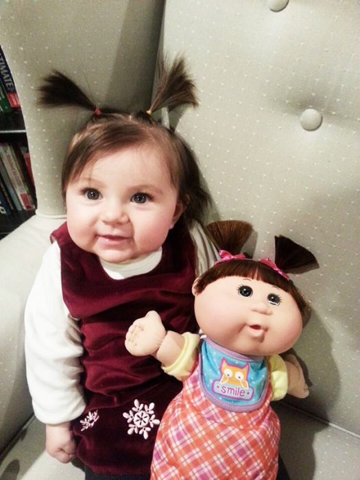 niña sentada a su muñeca que luce de manera similar a ella 