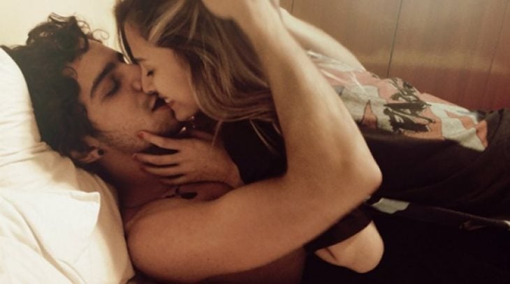 pareja de novios recostados en la cama besándose 