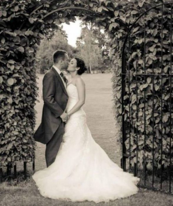 pareja de novios posando para una foto bajo un arco 