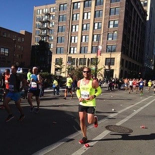 hombre usando una polera verde fosforecente corriendo en un maratón 