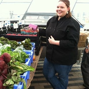 mujer gordita parada en un mercado comprando verduras 