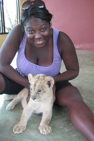 chica sosteniendo a un león bebe en medio de sus piernas 