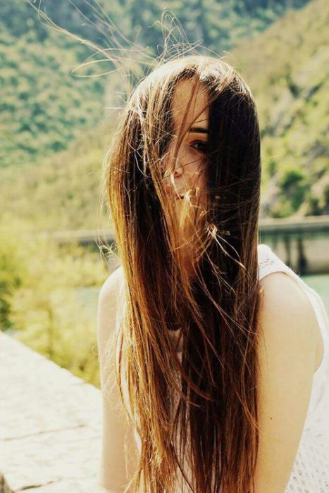 chica con el cabello liso en la cara gracias al viento 